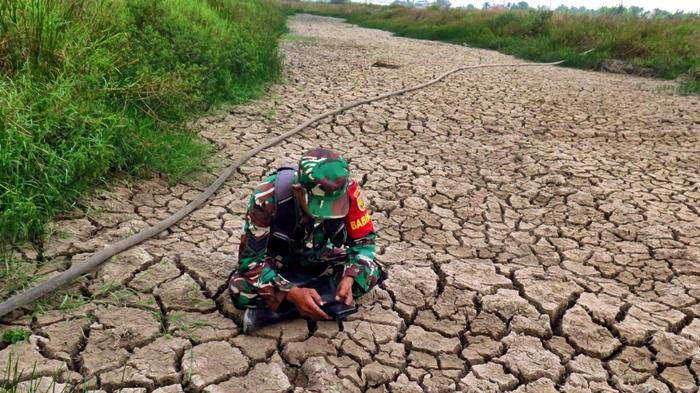 Babinsa-Karyajaya-duduk-bersila-sembari-memberikan-informasi-ke-posko-karhutla.jpg