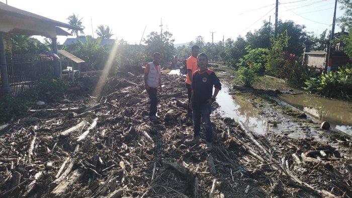 Banjir yang menerjang Desa Catur Karya, Kecamatan Balinggi, Kabupaten Parigi Moutong, Sulawesi Tengah, menyisakan tumpukan batang kayu di badan jalan, Selasa (30/5/2023).