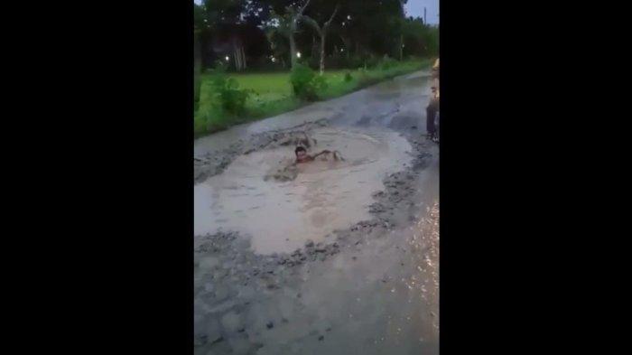 warga-berenang-di-kubangan-jalan-yang-berlubang-di-jalan-desa-jayamulya.jpg