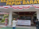 AKSI-Warga-memasang-spanduk-di-pintu-utama-Kantor-Kejaksaan-Tinggi-Papua-Ba.jpg