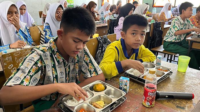 MBG - Murid SMPN 16 Pekanbaru sedang menikmati makan bergizi gratis di kelas saat jam istirahat, beberapa waktu lalu.