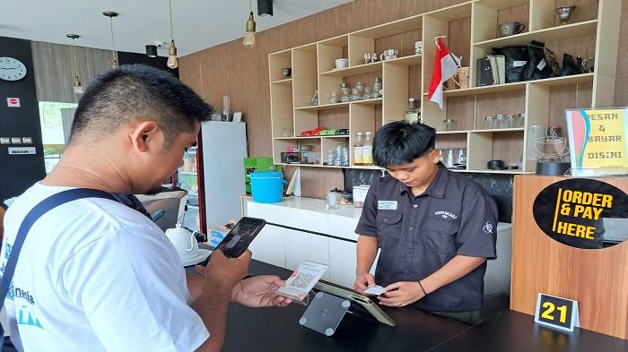 Seorang pembeli melakukan scan QR Code untuk melakukan pembayaran minuman kopi