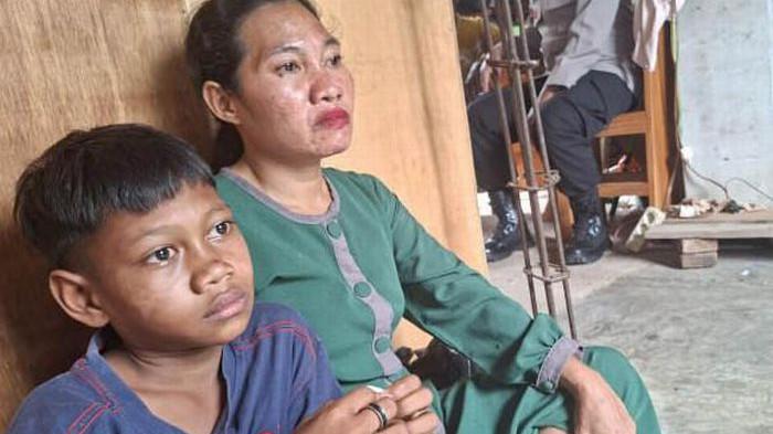 Lindawati, istri Hamzah duduk terpaku bersama seorang anaknya Muhammad