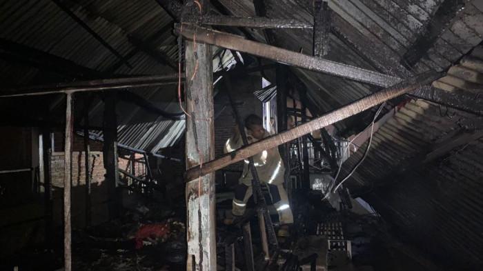 etugas BPBD Aceh Besar melakukan pendinginan terhadap dua bangunan yang terbakar 1