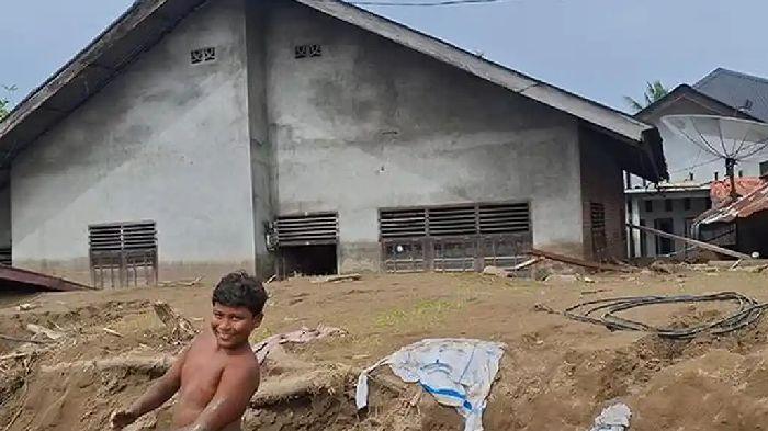 Seorang-anak-bermain-di-depan-rumah-yang-terkubur-dengan-lumpur-banjir-bandang-Pidie-Jaya.jpg