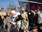 Orang-orang-berjalan-melewati-gerbang-untuk-memasuki-perbatasan-Rafah-ke-Mesir-di-Jalur-Gaza.jpg