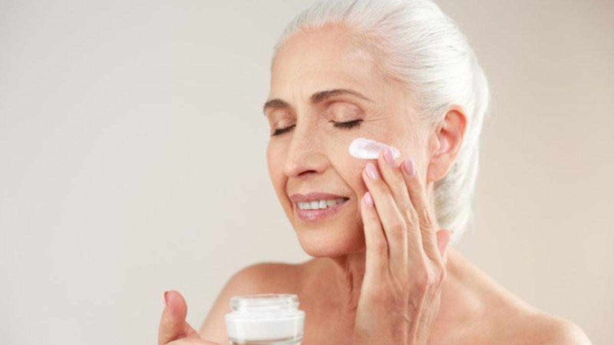 Ilustrasi wanita menggunakan moisturizer anti aging untuk mengencangkan kulit wajah.