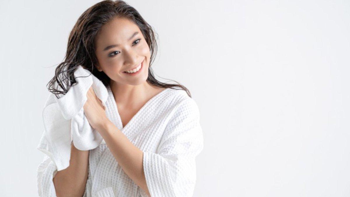 Ilustrasi wanita membersihkan rambut menggunakan shampo bebas SLS.