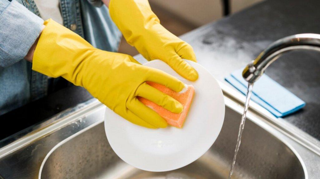 Ilustrasi mencuci piring dengan sarung tangan.