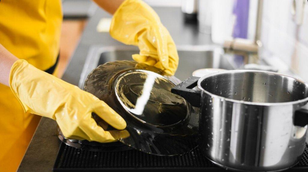 Ilustrasi mencuci piring dengan sarung tangan.