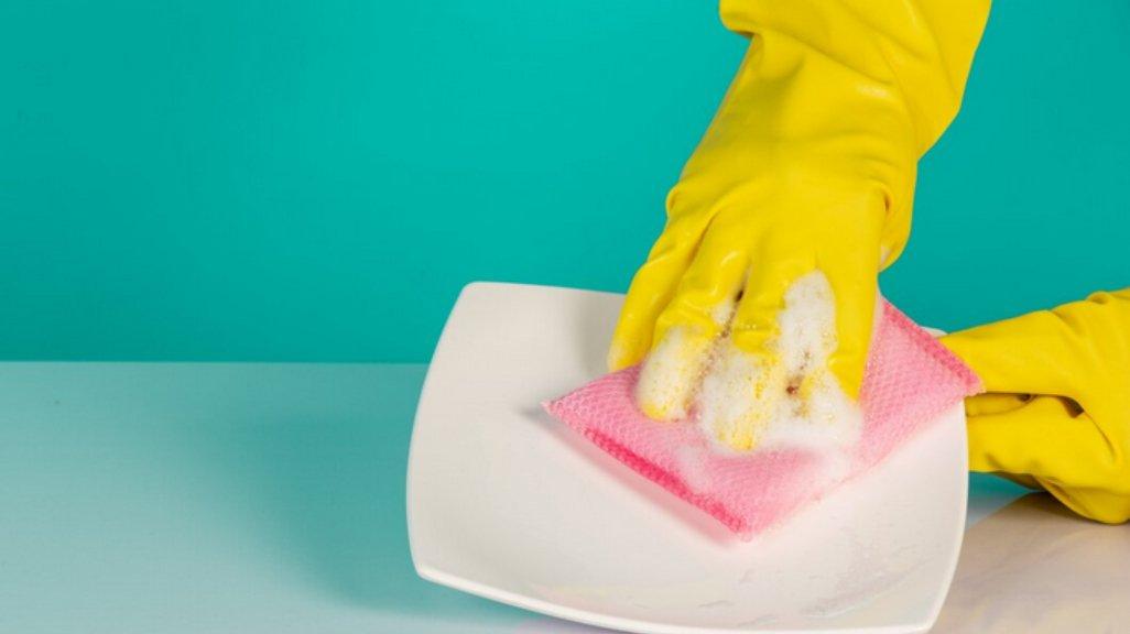 Ilustrasi mencuci piring dengan sarung tangan.