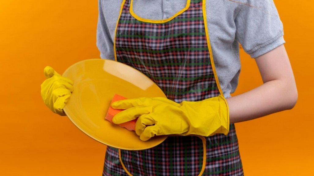 Ilustrasi mencuci piring dengan sarung tangan.