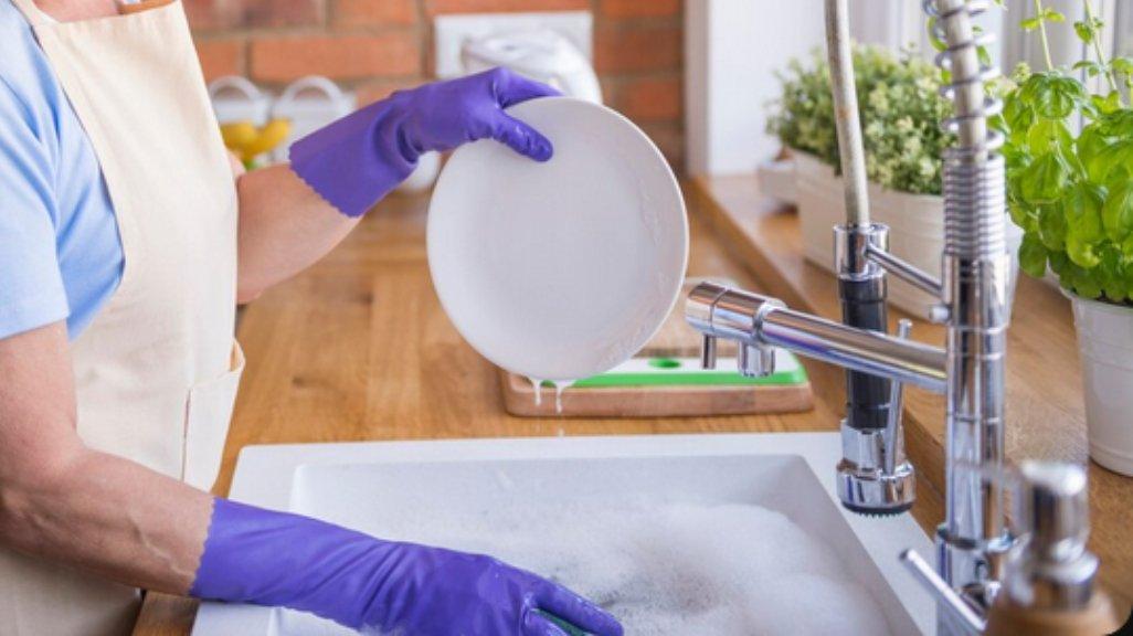 Ilustrasi mencuci piring dengan sarung tangan.