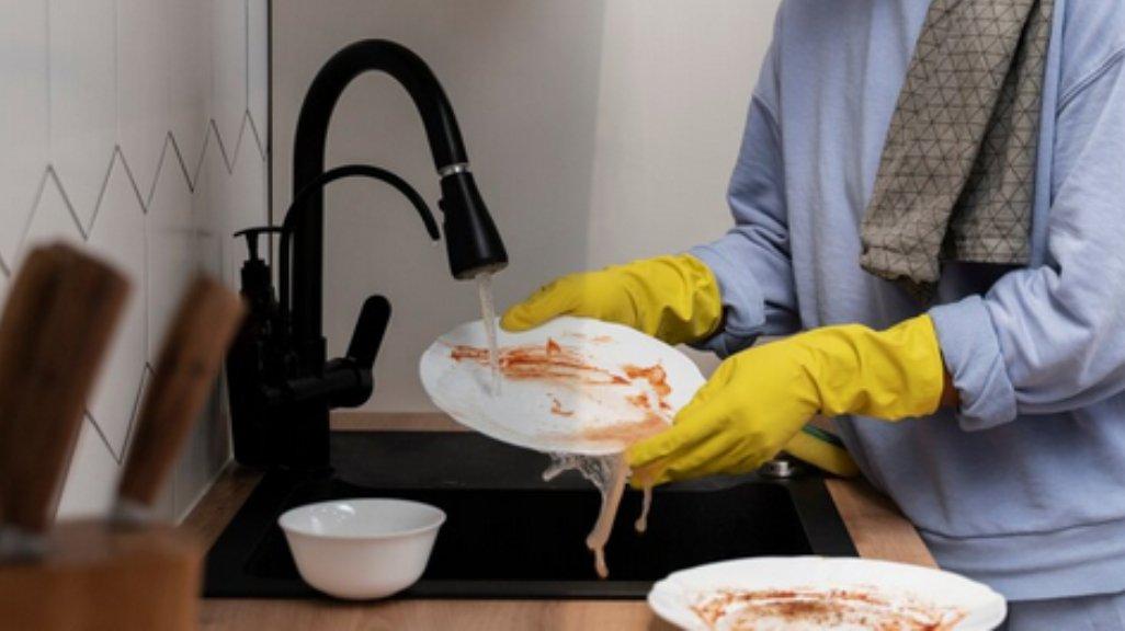 Ilustrasi mencuci piring dengan sarung tangan.