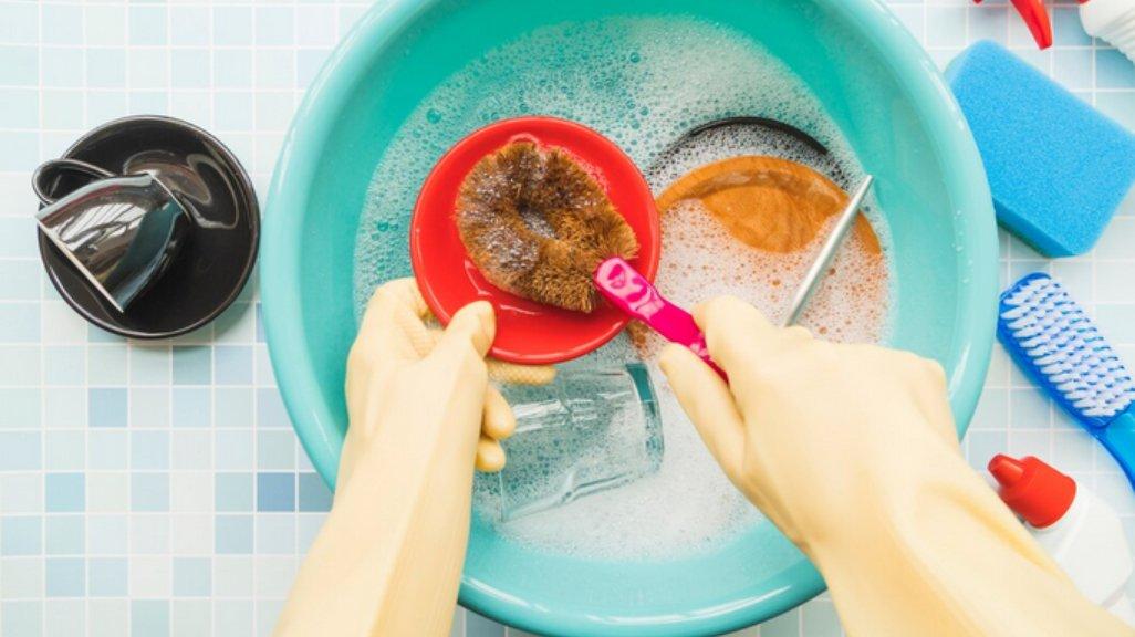 Ilustrasi mencuci piring dengan sarung tangan.