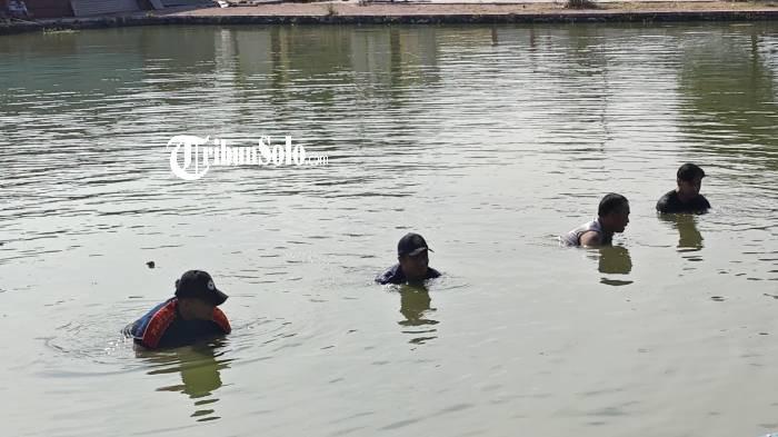 TANGAN KOSONG. Tim Pemadam Kebakaran (Damkar) Satpol PP Kabupaten Sukoharjo mengevakuasi sebuah handphone (HP) yang tercebur di Telaga Pakujoyo, Gayam, Sukoharjo, Minggu (3/5/2026) pagi. Mereka mencari pakai tangan kosong.