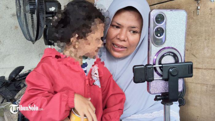 LIVE TIKTOK - Dian Aruna Mahesi (34), bersama anak bungsunya, Aira Cahya Mekarsari (4) sedang live TikTok di rumahnya, Kamis (8/1/2026). Dian berharap memperoleh pemasukan untuk membantu kebutuhan sehari-hari keluarga.