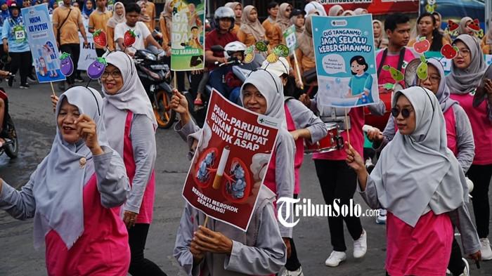 Kontingen berpakaian pink-abu dari tenaga kesehatan antusias membawa poster edukatif