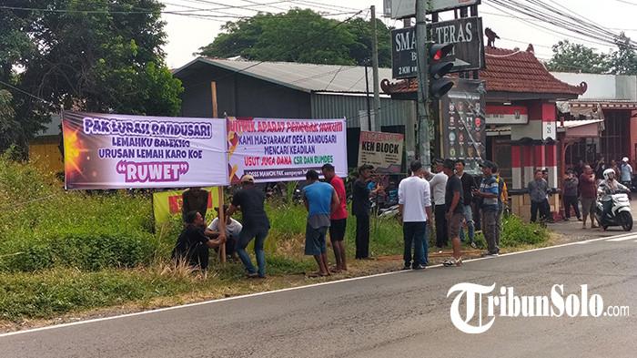 PASANG SPANDUK PROTES. Puluhan warga memasang spanduk protes sebagai buntut penyerobotan tanah kas desa di pinggir jalan Solo-Semarang, Minggu (21/9/2025). Pemasangan spanduk ini sebagai buntut penyerobotan tanah kas desa yang diduga dilakukan oleh Kepala Desa (Kades) Satu Budiyono.