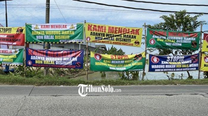 SPANDUK PENOLAKAN - Sebanyak 20 spanduk penolakan terhadap keberadaan kuliner non halal terpajang di sepanjang Jalan Setya Dharma, Dukuh Sudimoro, Desa Parangjoro, Kecamatan Grogol, Kabupaten Sukoharjo, Jawa Tengah, Senin (20/4/2026).