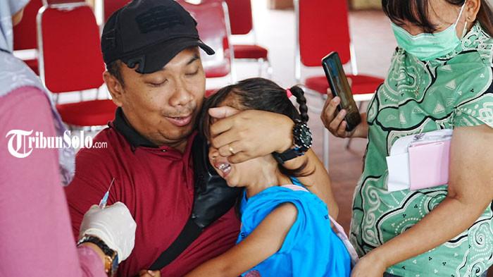 VAKSIN CAMPAK - Seorang anak menangis saat menerima suntikan vaksin campak, didampingi orang tuanya di Balai Desa Kraguman, Klaten, Selasa (31/3/2026). ORI campak di Kabupaten Klaten disambut positif oleh para orang tua. Mereka mengaku lebih tenang setelah anaknya menerima vaksin.