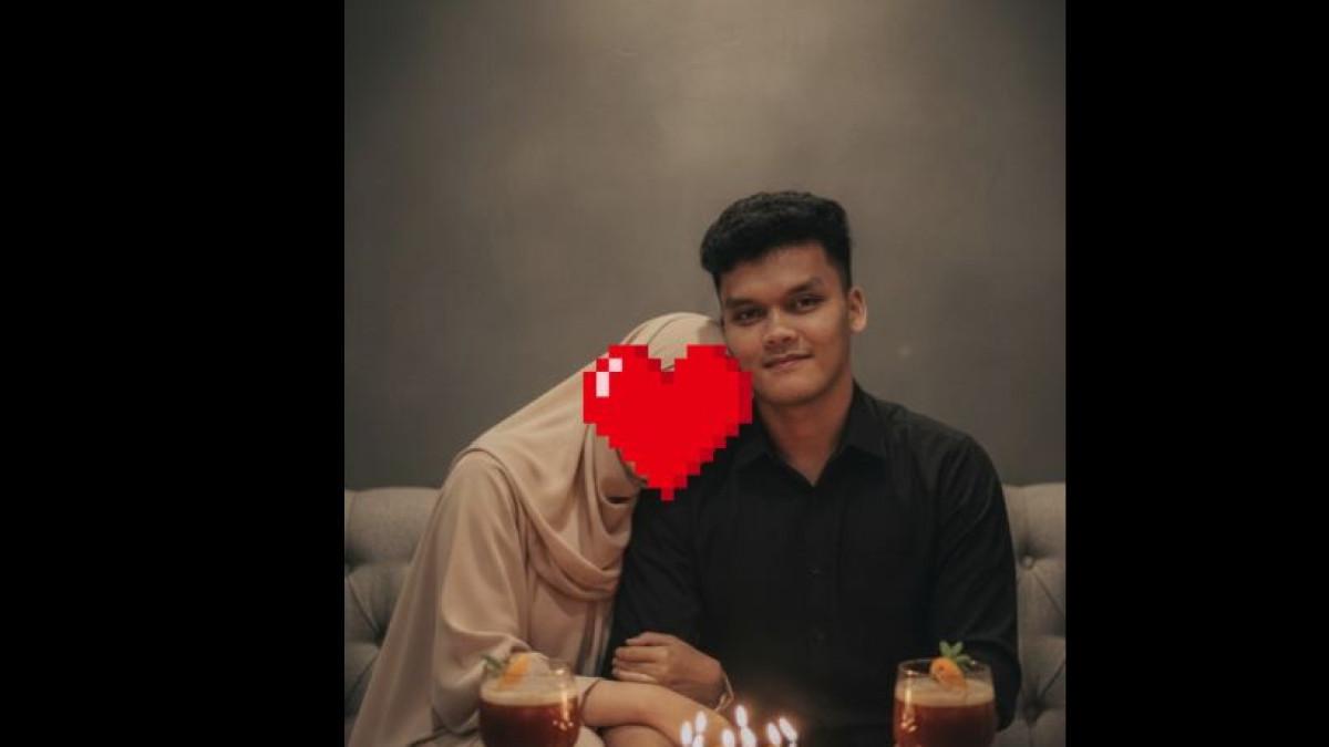 Pasangan tersebut tampak duduk berdampingan di sebuah sofa dengan kue ulang tahun lengkap dengan lilin menyala di hadapan mereka.