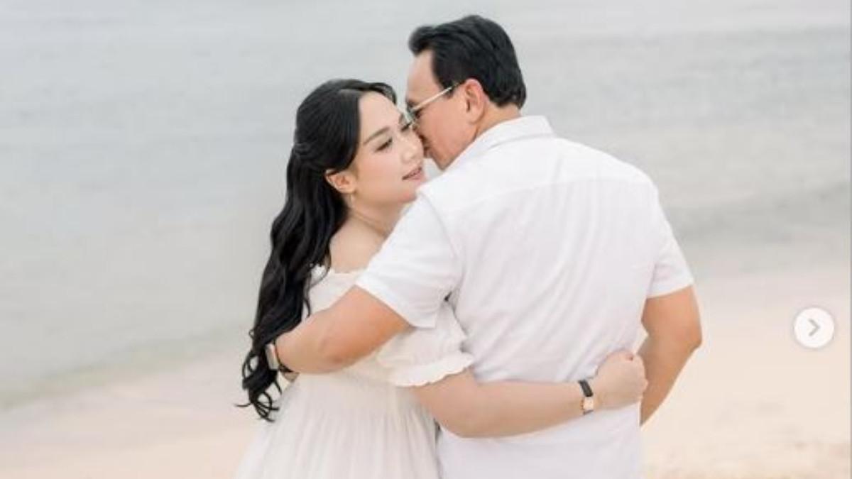 HAMIL ANAK KETIGA - Puput sendiri tampil anggun dengan gaya resort, mengenakan long dress putih model off shoulder lengan pendek kerut, dilengkapi anting-anting model raindrop serta jam tangan strap hitam.