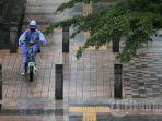 warga-menaiki-sepeda-listrik-melintas-saat-turun-hujan.jpg