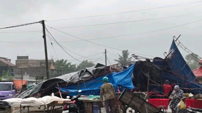 PUTING BELIUNG – Pasar Smart Pasangkayu setelah diterjang angin puting beliung pada Jumat (27/2/2026) pagi. Tampak lapak pedagang berantakan dan beberapa warga serta petugas mulai merapikan sisa-sisa tenda dan dagangan yang rusak akibat cuaca ekstrem tersebut.