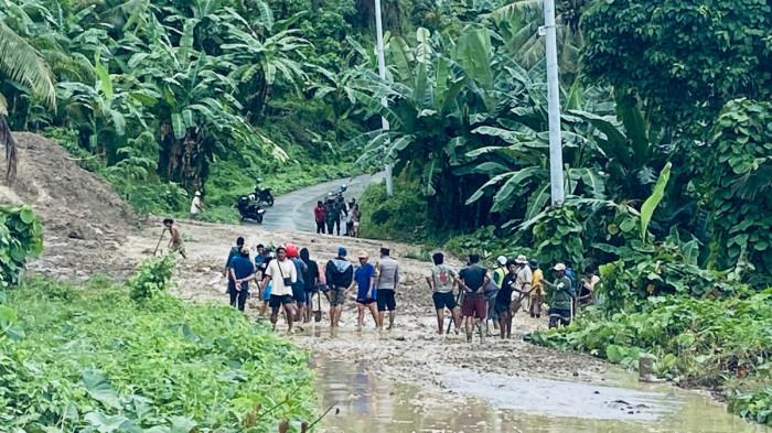 TANAH LONGSOR - Puluhan warga dan aparat TNI-Polri saat membersihkan tanah dan lumpur dari longsor yang menutup akses jalan di Desa Pangiang, Kecamatan Bambalamotu, Kabupaten Pasangkayu, Kamis (8/1/2026). Sebanyak 9 dusun yang terisolir akibat longsor ini.
