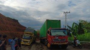 Dua-truk-yang-mencoba-melewati-kubangan-tanah-mobil-orange-terjebak-sejak-Minggu-Subuh.jpg