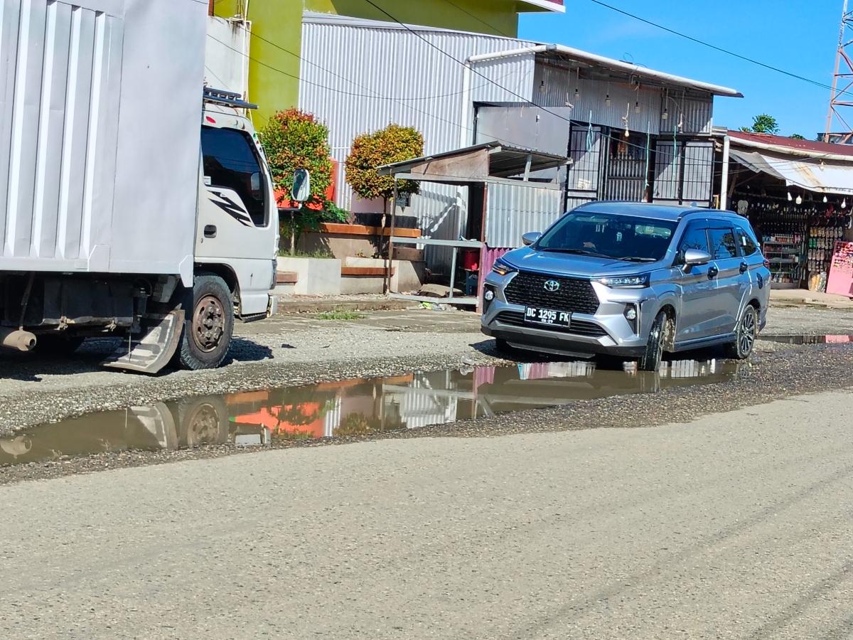 Sebuah-mobil-parkir-di-atas-genangan-air-di-jalan-berlubang-depan-Masjid-Nurul-Hidayah-Topoyo.jpg