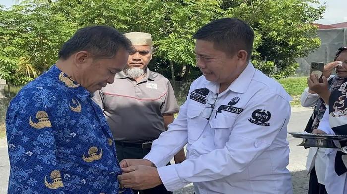 GURU SMAN 1 LUTRA - Momen Rasnal dan Abdul Muis saat tiba di SMAN 1 Luwu Utara, Rabu (19/11/2025). Kedua guru tersebut disambut siswa dan guru. Dalam momen itu, Kepala SMAN 1 Lutra, Safruddin (kanan) langsung memakaikan seragam Korpri kepada Rasnal (kiri).