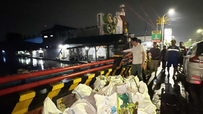 BANJIR - Bupati Sidoarjo Subandi saat memantau banjir di Sidokare, Rabu (19/11/2025) malam. Alat berat dikerahkan untuk membersihkan sampah yang menumpuk di Jembatan Kuthuk.