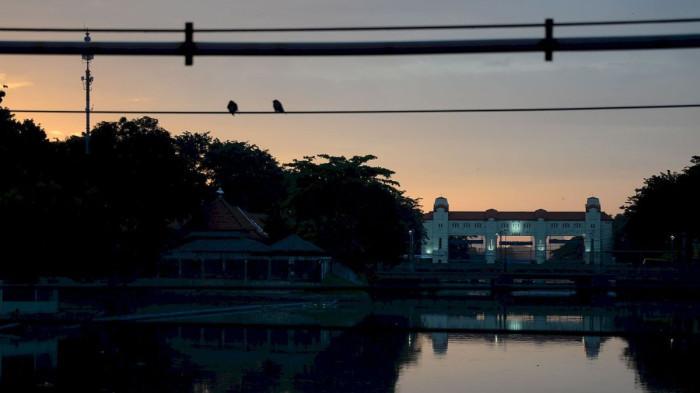 CERAH - Suasana pagi hari dan matahari batal terlihat akibat cuaca cenderung berawan di atas sungai kawasan Jl Wonokromo Surabaya, Jumat (27/3/2026).