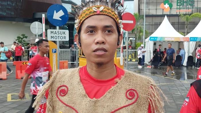 TAMPIL  UNIK : Safi (30), salah satu perseta event RS BHC Run 2025 tampil unik mengenakan baju adat Papua, Minggu (8/2/2026). (FOTO/HANGGARA PRATAMA)