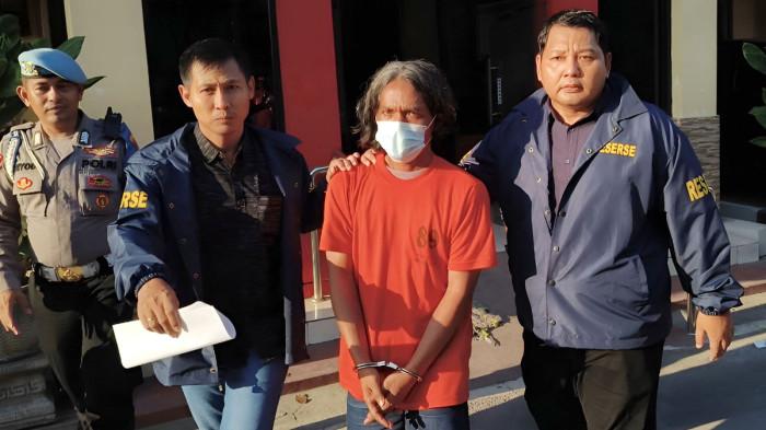 SADIS - Tersangka Satuan (42) dikeler petugas saat menjalani pemeriksaan atas kejahatan penganiayaan yang menyebabkan mertua meninggal dan melukai istri, di Satreskrim Polres Mojokerto, Jawa Timur, Kamis (7/5/2026).