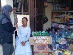 Wina-menunggui-tokonya-yang-baru-diisi-barang-barang.jpg