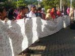 ratusan-wali-murid-membentangkan-kain-berwarna-putih-sepanjang-sekitar-10-meter.jpg