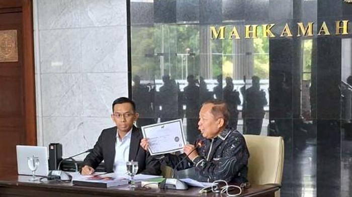 Hakim Mahkamah Konstitusi (MK) Arsul Sani menunjukkan ijazah doktoralnya