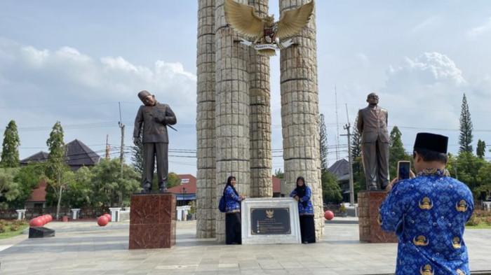 Sejumlah PPPK yang baru mendapat SK pengangkatan ketika berfoto di patung Soekarno-Hatta dengan latar tugu bambu runcing yang berlokasi di Alun-alun Indramayu, Senin (17/11/2025)