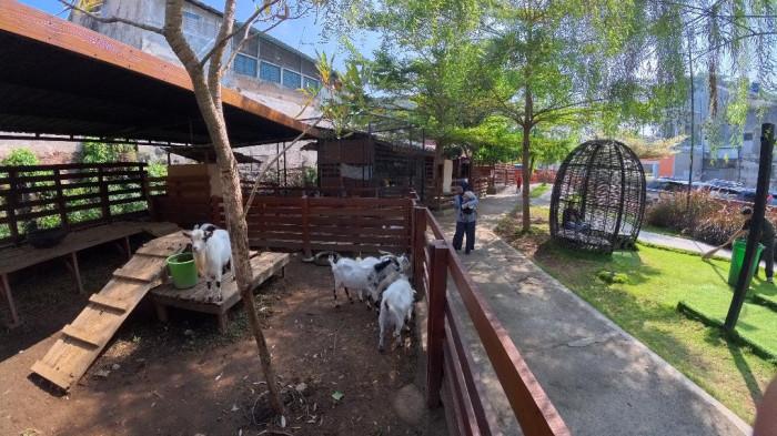 LIBURAN - Seorang pengunjung menggendong anaknya di dekat kandang kambing yang berada di Piataland, Kota Malang. Tempat wisata Piataland bisa menjadi alternatif liburan di tengah kota bersama buah hati tercinta.