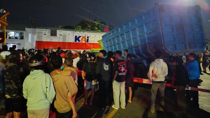 LAKA KERETA API - Warga berkerumun menyaksikan peristiwa kecelakaan KA Dhoho dan truk muatan pasir di perlintasan Jl Imam Bonjol, Kota Blitar, Selasa (28/4/2026) malam. Satlantas Polres Blitar Kota kini menyoroti dugaan aksi nekat sopir truk yang tetap melintas saat palang pintu mulai menutup hingga akhirnya mogok di tengah rel.