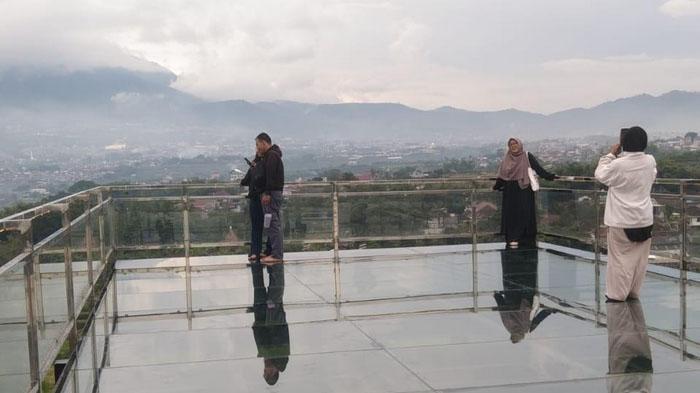 BERFOTO - Wisatawan berfoto di atas jembatan kaca di Malang Skyland yang terletak di Kecamatan Karangploso, Kabupaten Malang, Senin (22/12). Malang Skyland bisa menjadi tempat wisata rekomendasi saat libur Natal dan Tahun Baru (Nataru).
