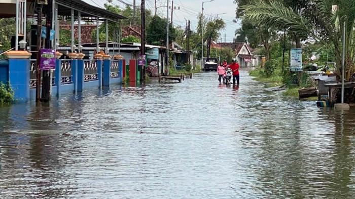 MOGOK – Pengendara sepeda motor harus menuntut kendaraannya karena mogok saat melintasi genangan air di Desa Kedungbanteng, Sabtu (27/12/2025). Banjir di kawasan ini sudah terjadi sekira satu bulan. Dan sudah menjadi langganan setiap musim hujan