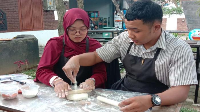 BIKIN PIZZA - Pasangan Enggar dan Alin saat membentuk adonan tepung menjadi pizza, Kamis (4/9/2025). Kedai pizza bernama Cissipizza di Kota Malang menawarkan sensasi pengalaman membuat pizza sendiri.
