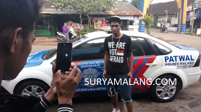 Mahasiswa Ini Berpose di Depan Mobil Patwal Polisi Sebelum Dipaksa Pulang ke Sumba NTT