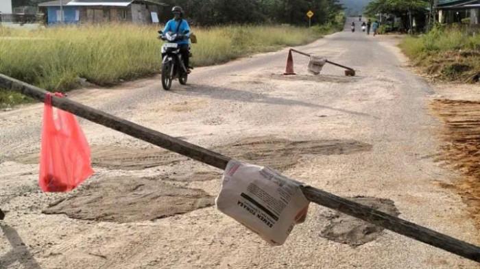 FASILITAS: Lubang jalan di depan Kantor Pengadilan Negeri Bobong, Pulau Taliabu ditambal warga, Minggu (8/2/2026)