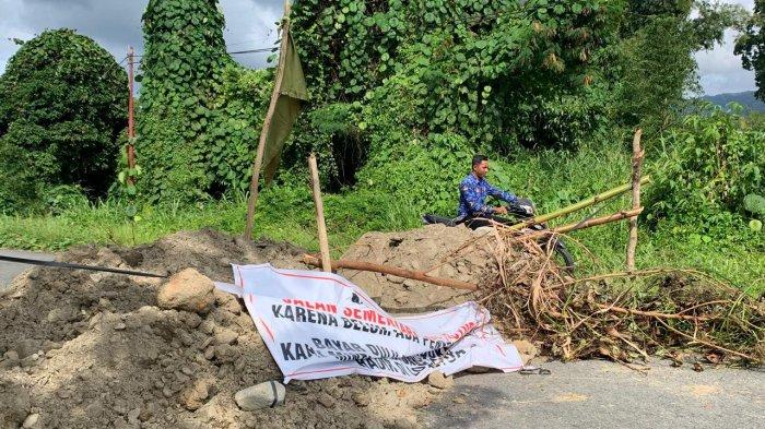 TUNTUTAN: Tampak seorang ASN Pemkab Halmahera Selatan berupaya melewati jalan yang dipalang menggunakan timbunan tanah, Kamis (12/3/2026).