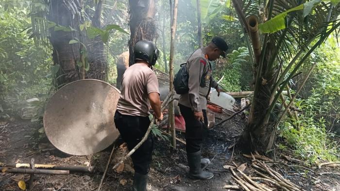 MIRAS: Tampak dua anggota Polsek Bacan Timur, Halmahera Selatan musnahkan sebuah lokasi penyulingan miras jenis cap tikus di Desa Wayamiga beberapa waktu lalu.